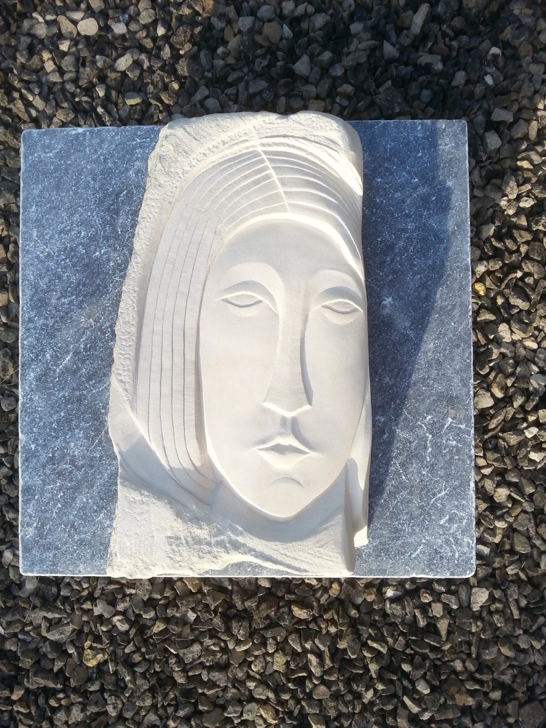 Carved stone stylised face in Caen limestone